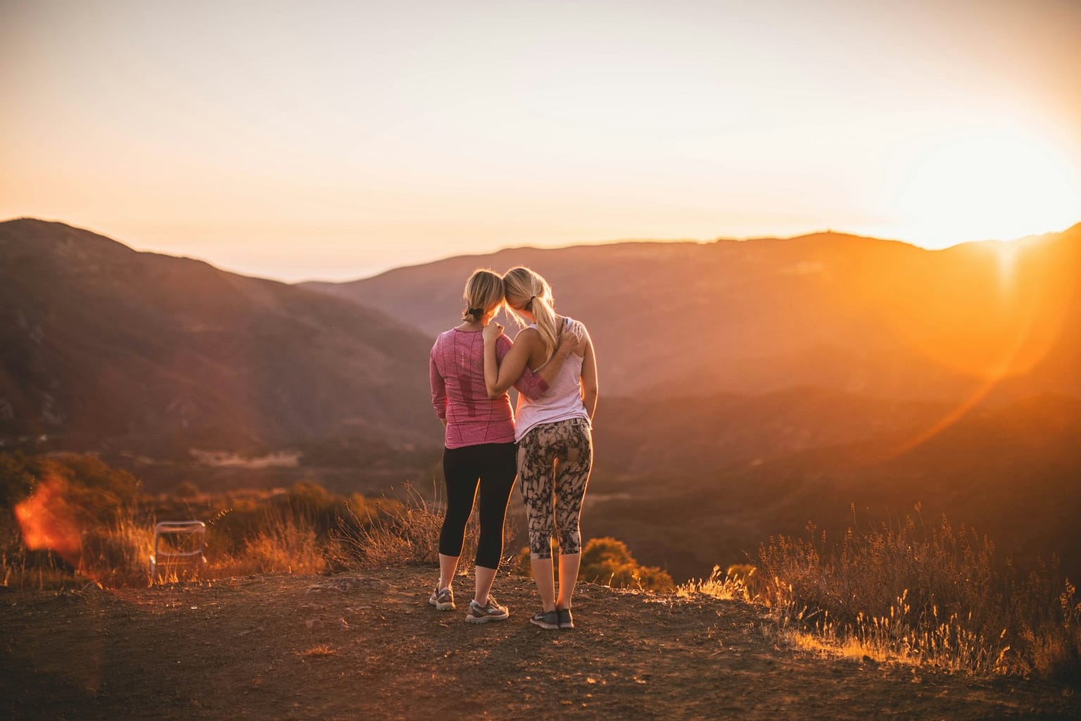 two women on a hike at sunset overlooking the mountains